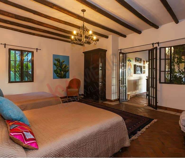 Beautiful colonial bedroom with rustic wooden beams and large windows overlooking Allende Dam.