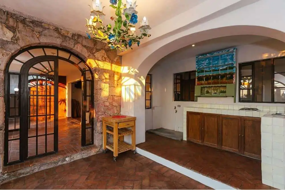 Exquisite Colonial Interior with Rustic Charm Charming colonial estate interior featuring stone walls, arched doorways, and vibrant decor in San M.