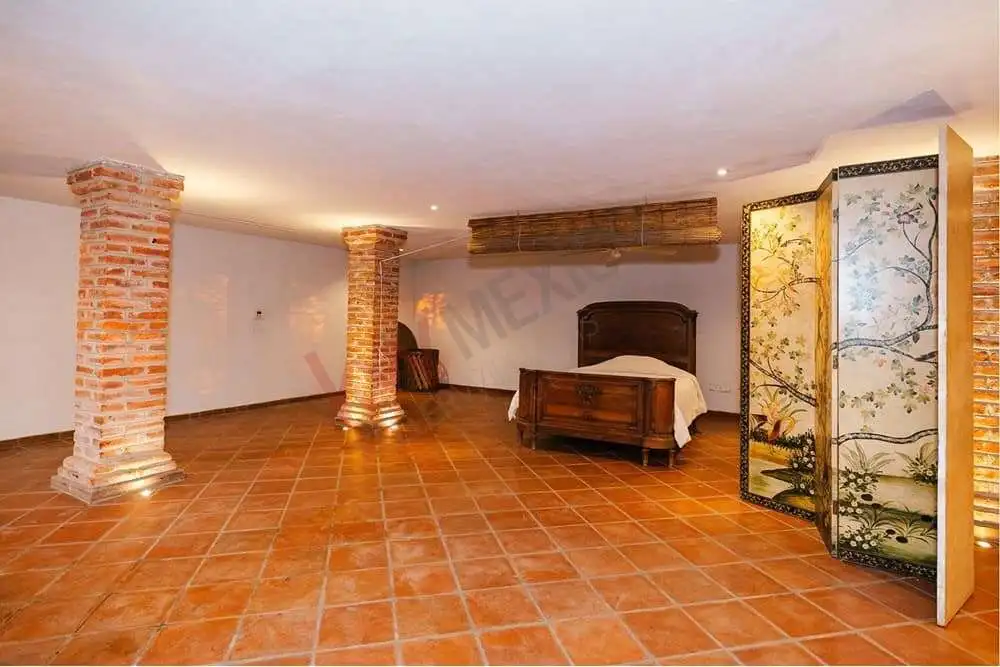 Elegant Colonial Bedroom with Dam Views | Rancho de Cabras Spacious bedroom with rustic brick columns and dam views in San Miguel de Allende.