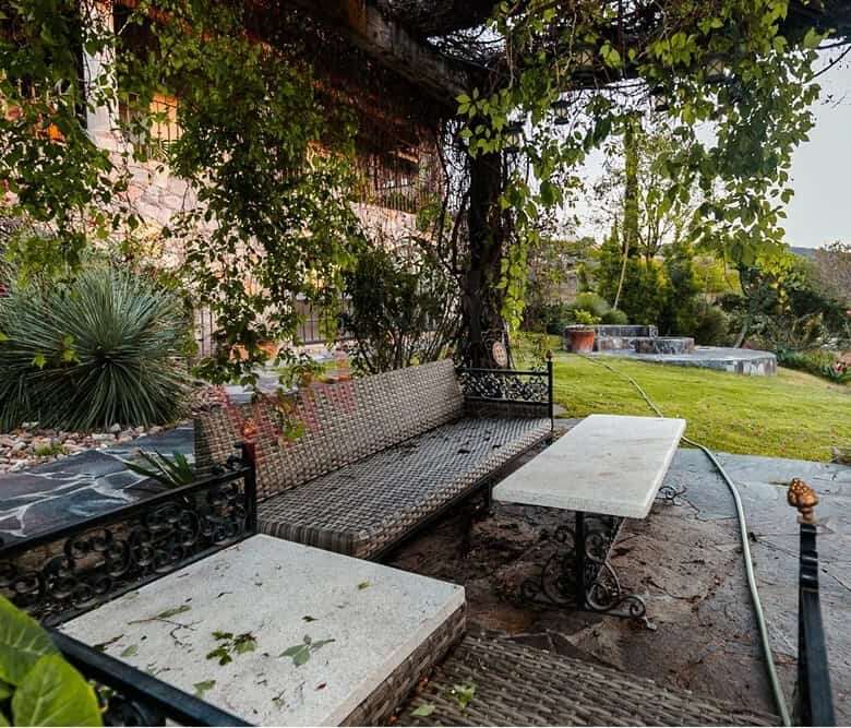Outdoor seating with garden views and shaded trees in a peaceful estate setting.