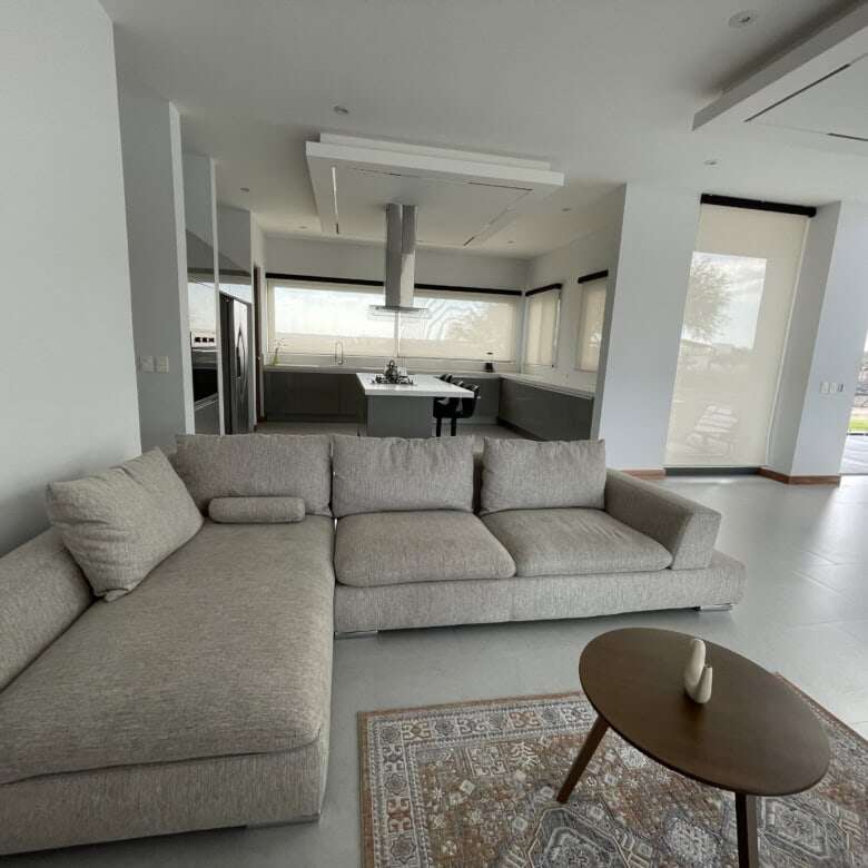 Spacious living area featuring a comfortable L-shaped sofa, natural light, and contemporary design e.