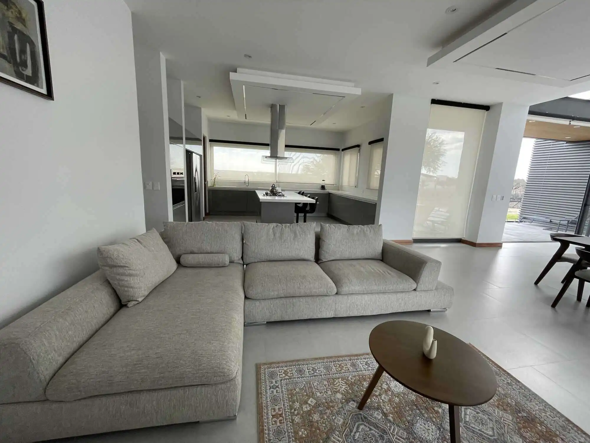 Spacious living area featuring a comfortable L-shaped sofa, natural light, and contemporary design e.