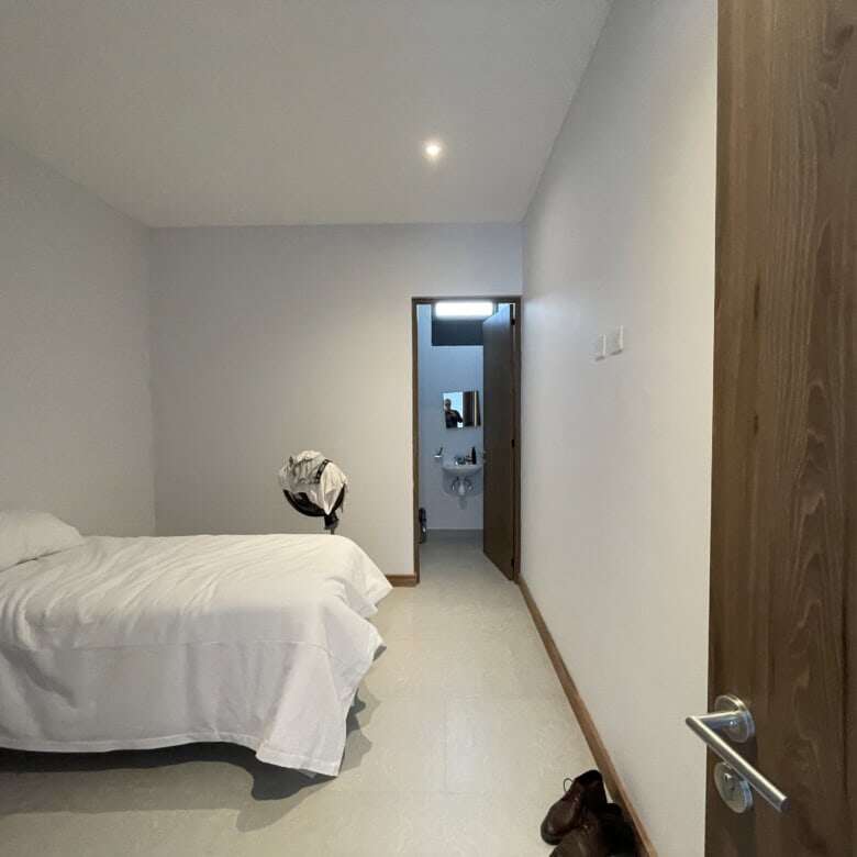 Spacious bedroom featuring a minimalist style with white bedding and simple decor in a high-end vine.