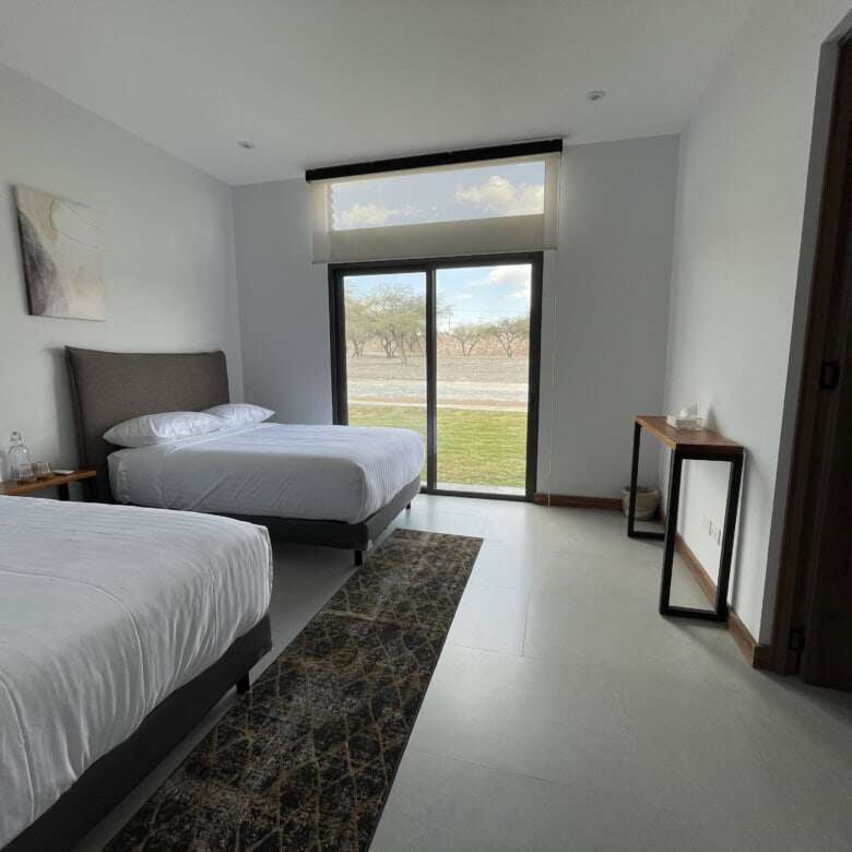 Spacious bedroom in a vineyard estate with modern decor and large windows overlooking scenic views.