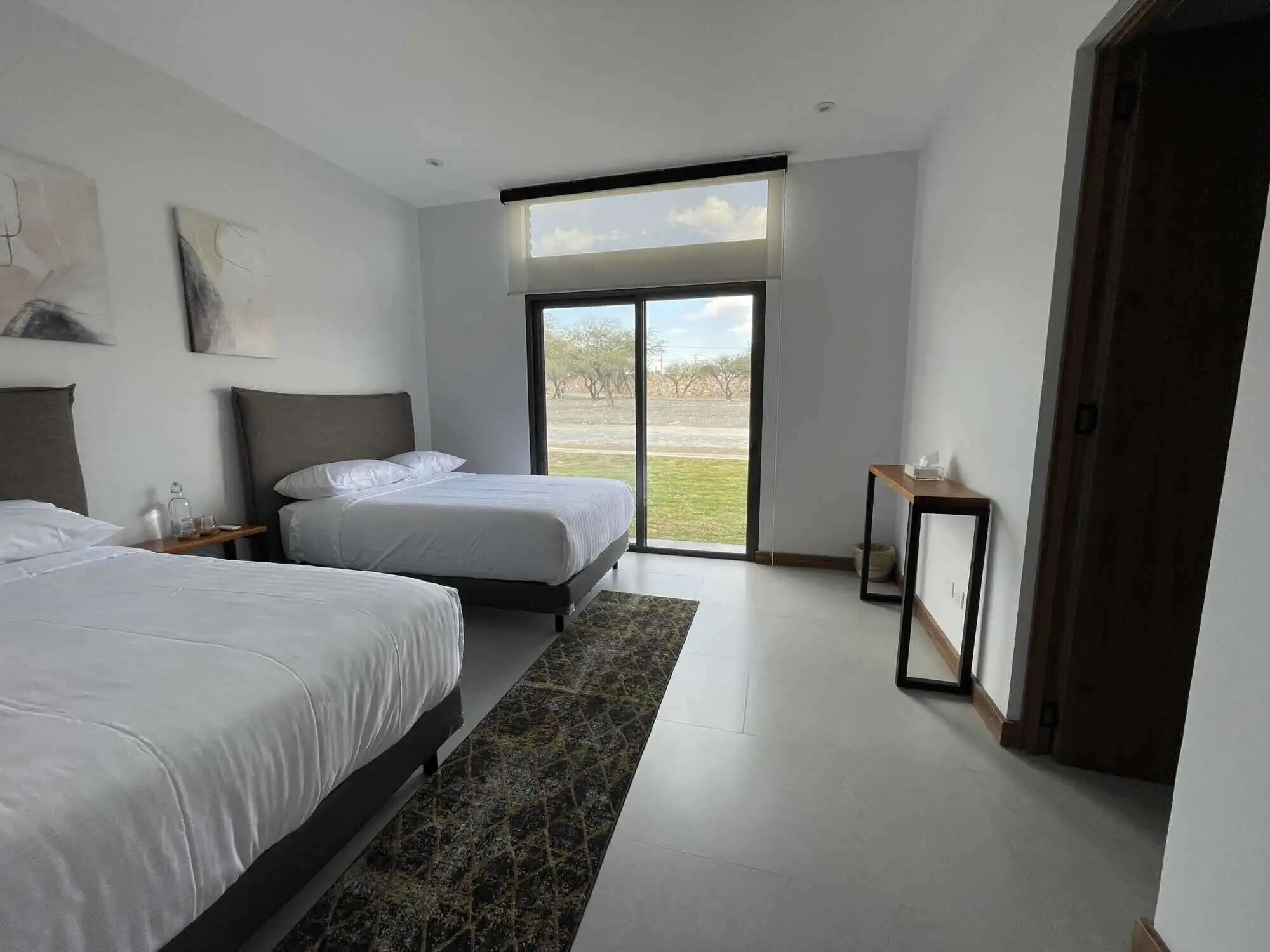 Spacious bedroom in a vineyard estate with modern decor and large windows overlooking scenic views.