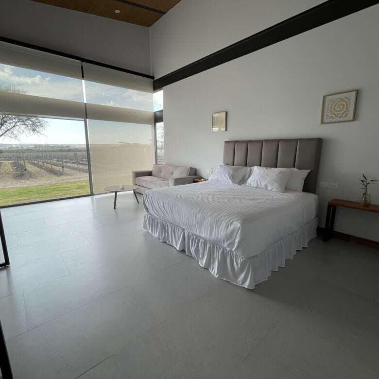 Elegant bedroom with large windows overlooking scenic vineyard views in San Miguel de Allende.