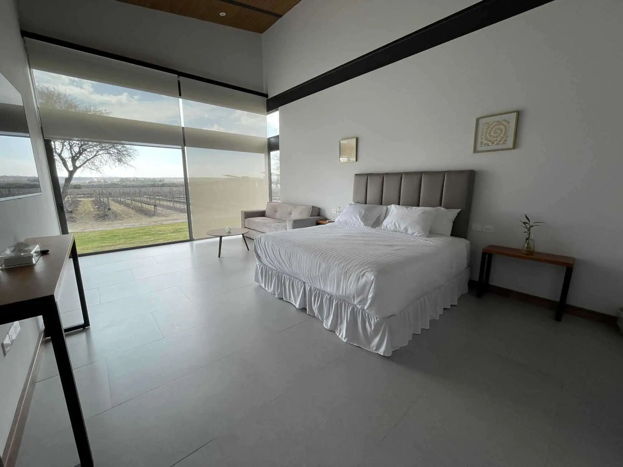 Elegant bedroom with large windows overlooking scenic vineyard views in San Miguel de Allende.
