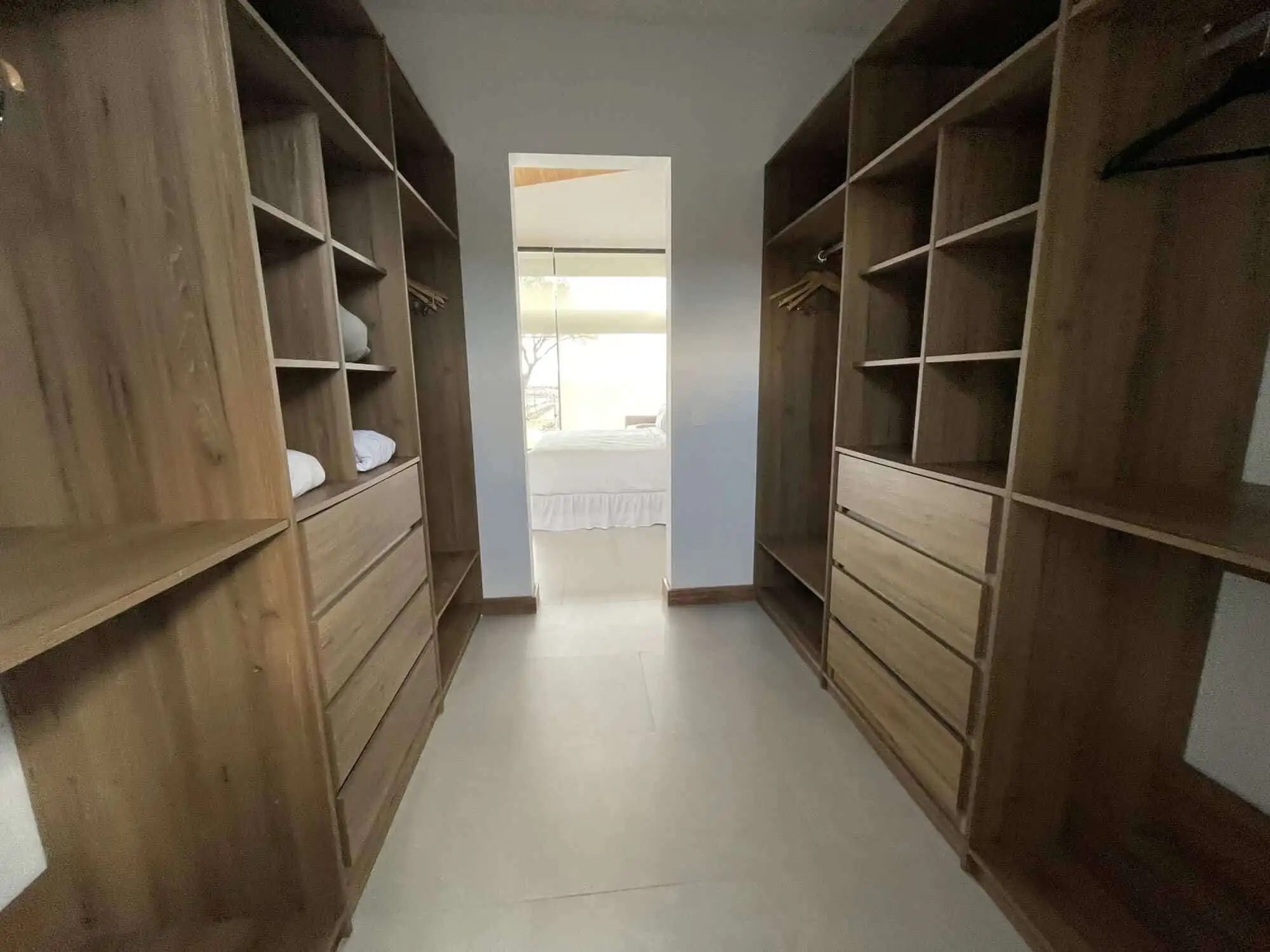 Elegant walk-in closet with wooden shelves and drawers.