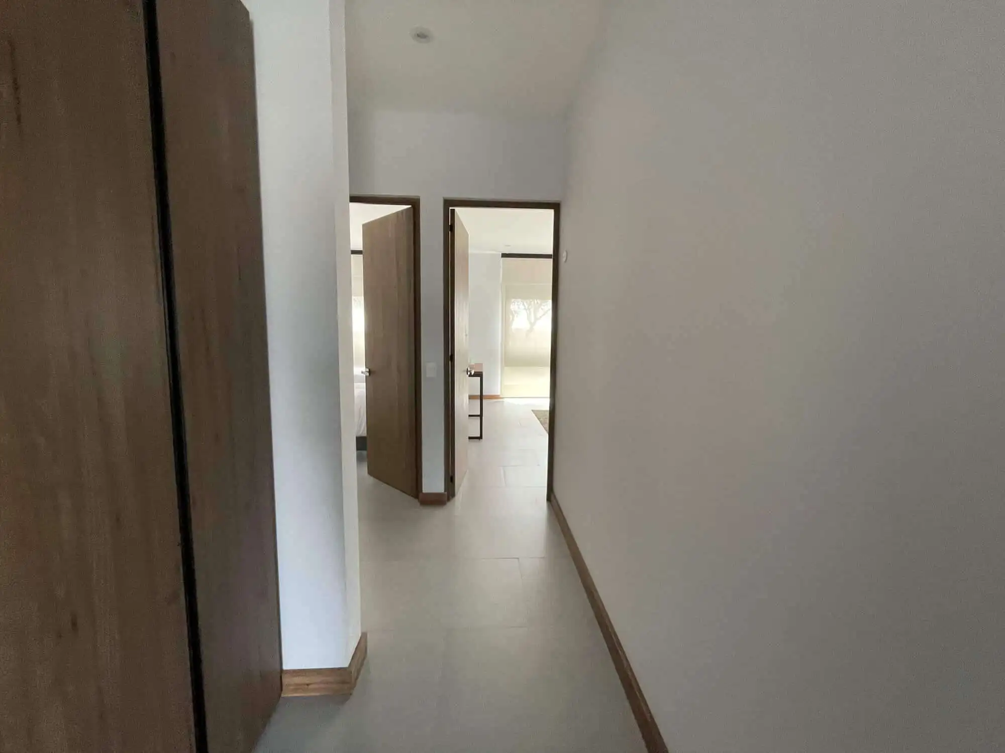 Spacious hallway with wooden accents leading to elegant rooms in a high-end property.