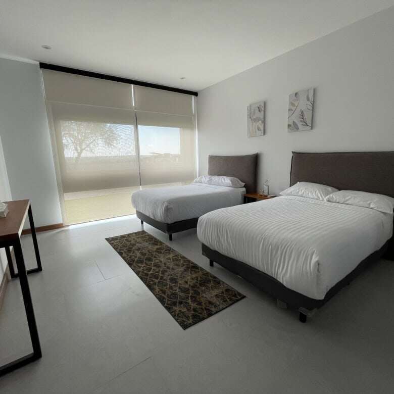 Modern bedroom with two comfortable beds and large window with scenic views.