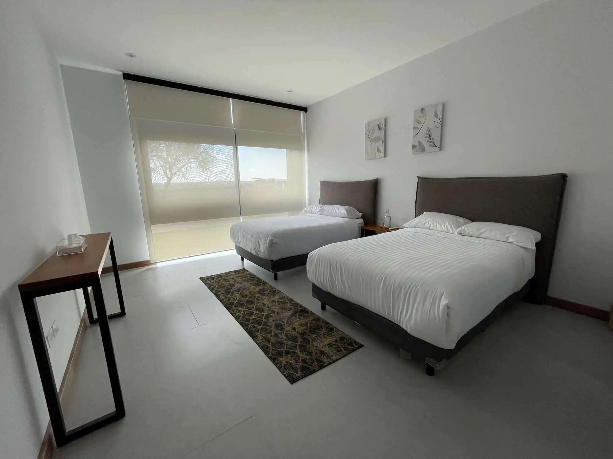 Modern bedroom with two comfortable beds and large window with scenic views.