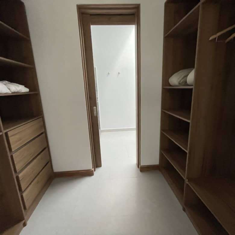 Elegant walk-in closet with wooden shelves and hanging space.