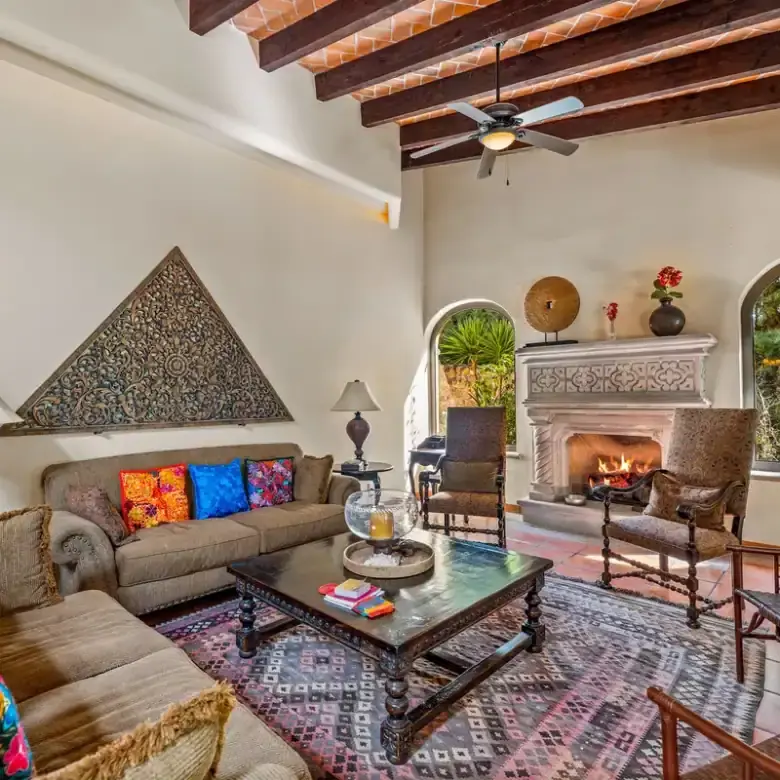Inviting living room with fireplace, colorful cushions, and wooden ceiling beams in Rancho Los Labra.