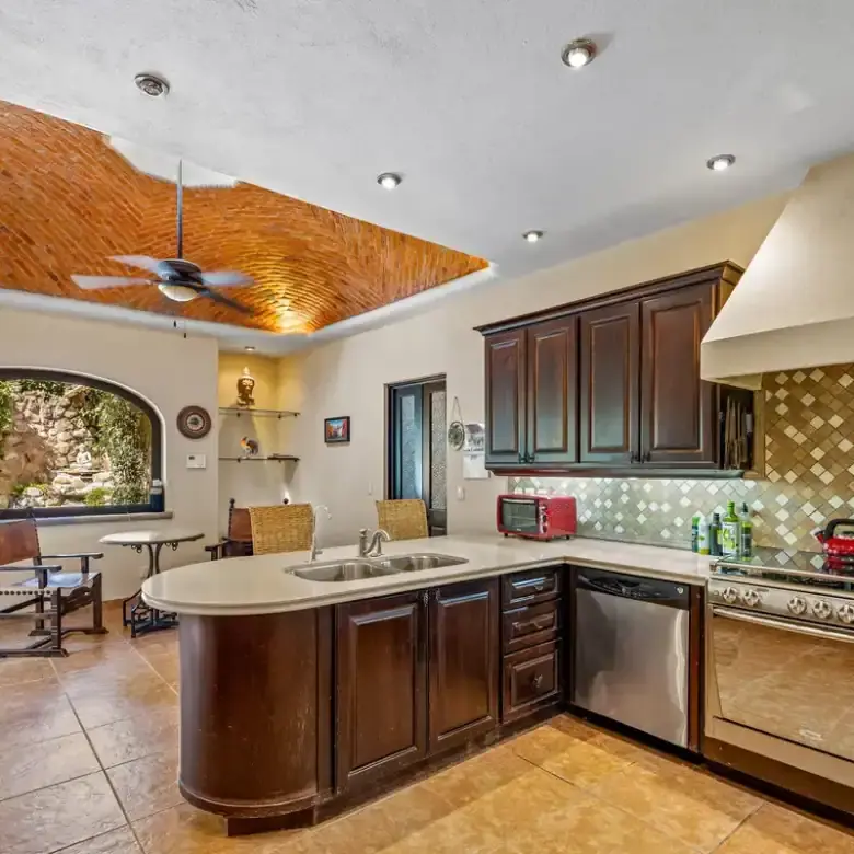 Spacious kitchen in Rancho Los Labradores featuring dark wood cabinets, a brick ceiling, and modern.