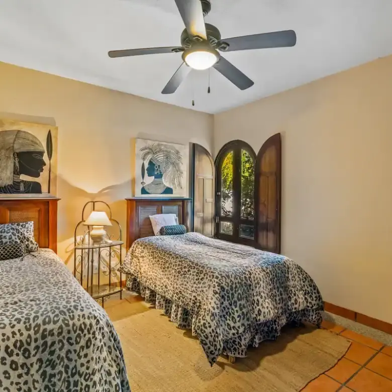 Beautiful bedroom with two beds, ceiling fan, and natural light in Rancho Los Labradores.