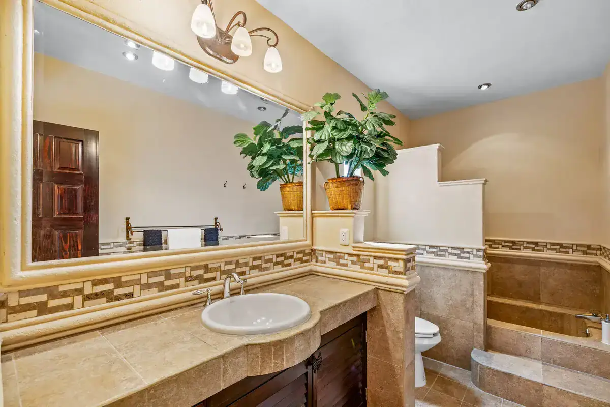 Modern bathroom with beige tiles and decorative accents in Rancho Los Labradores. Bathroom with beige tiles, large mirror, and decorative plant accents in Rancho Los Labradores.