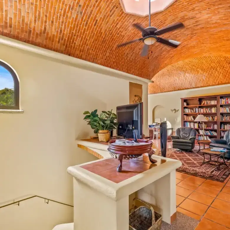 Cozy living room with vaulted brick ceiling and large bookshelf in Rancho Los Labradores.