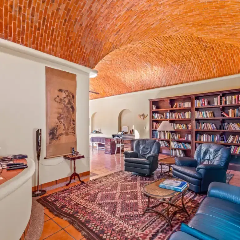 Cozy living room with brick vaulted ceiling, bookshelves, and comfortable armchairs.