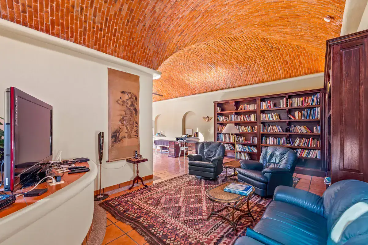 Modern living room with brick vaulted ceiling and cozy seating area. Cozy living room with brick vaulted ceiling, bookshelves, and comfortable armchairs.