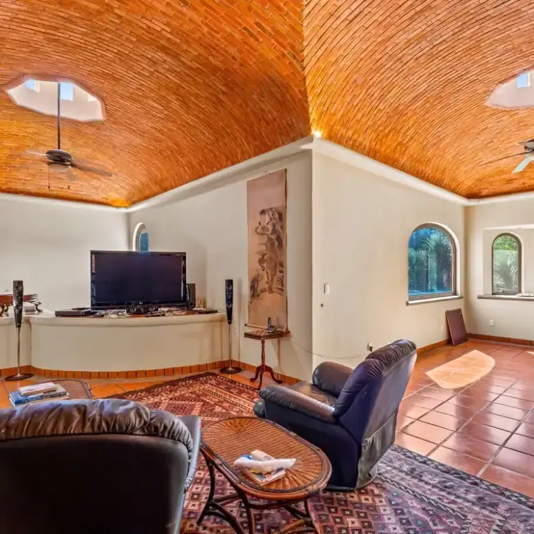 Spacious living area featuring a stunning brick vaulted ceiling and large arched windows overlooking.