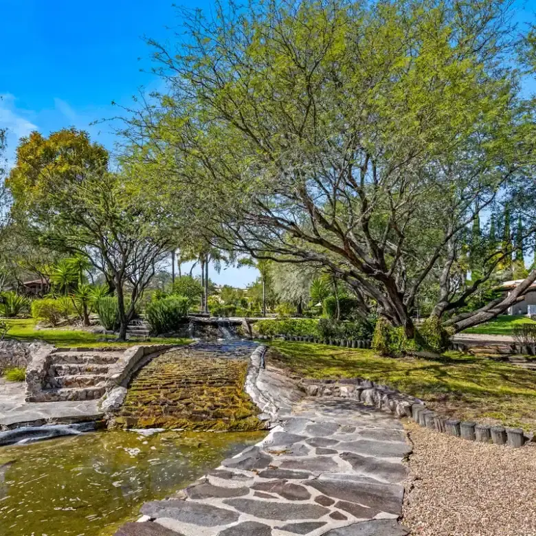 Beautiful lakefront home with lush trees and scenic water features in Rancho Los Labradores.