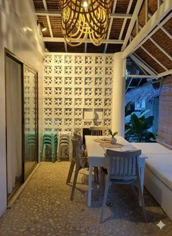 Indoor dining space with a white table, chairs, and decorative wall in a tropical house.