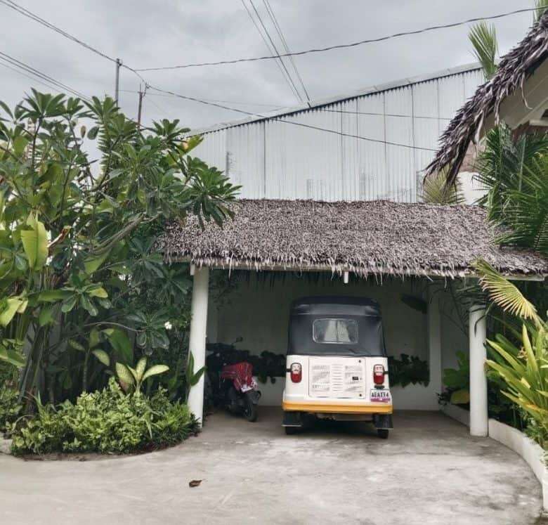 Cozy 3-bedroom house for sale in Siargao Island featuring a shaded carport and lush tropical garden.