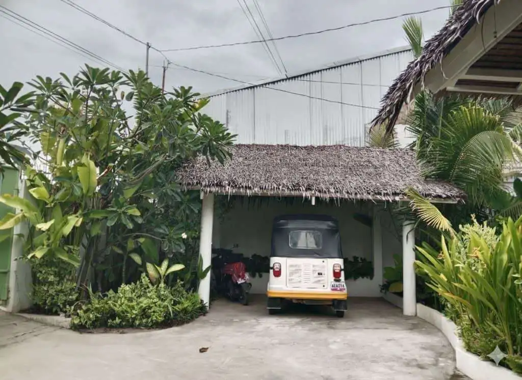Cozy 3-bedroom house for sale in Siargao Island featuring a shaded carport and lush tropical garden.