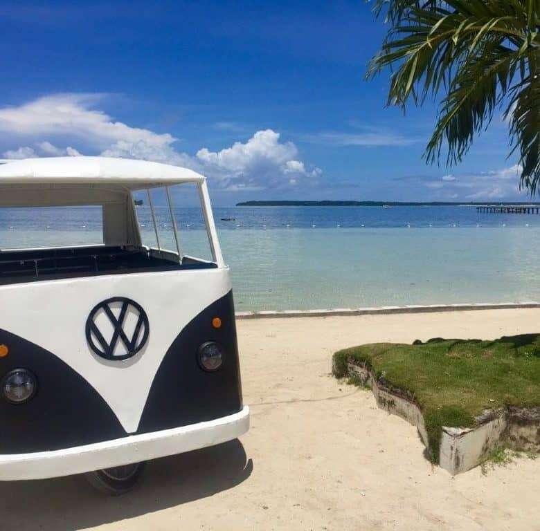 Vintage VW camper van on Siargao Island beach, tropical scenery, perfect for vacation rentals.
