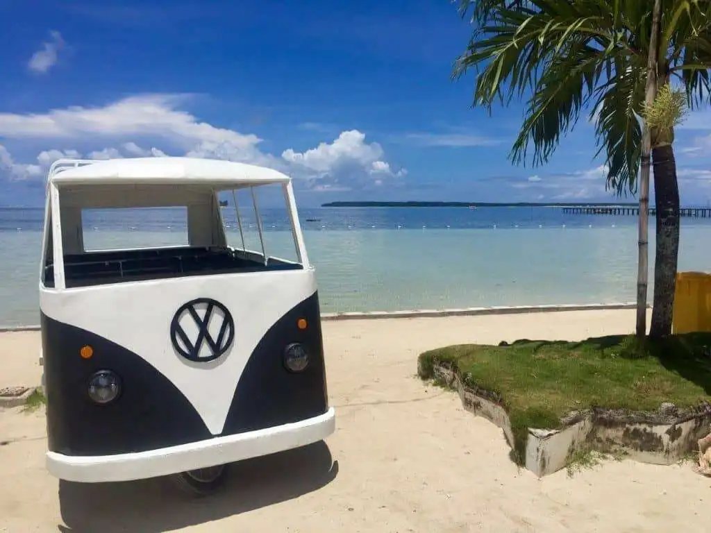 Vintage VW camper van on Siargao Island beach, tropical scenery, perfect for vacation rentals.
