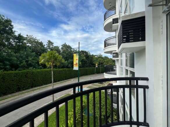 Bright apartment balcony overlooking lush greenery and a quiet street in Boracay.