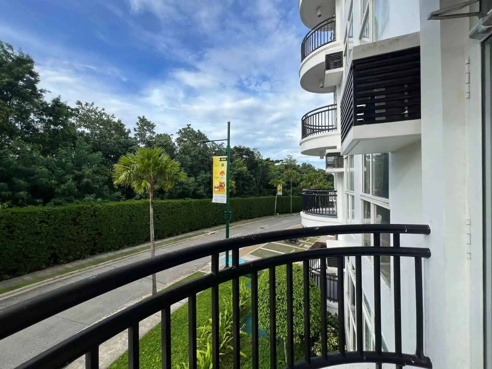 Bright apartment balcony overlooking lush greenery and a quiet street in Boracay.