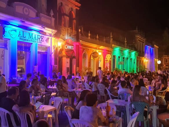 Vibrant illuminated restaurant exterior with outdoor dining and many guests enjoying the evening.