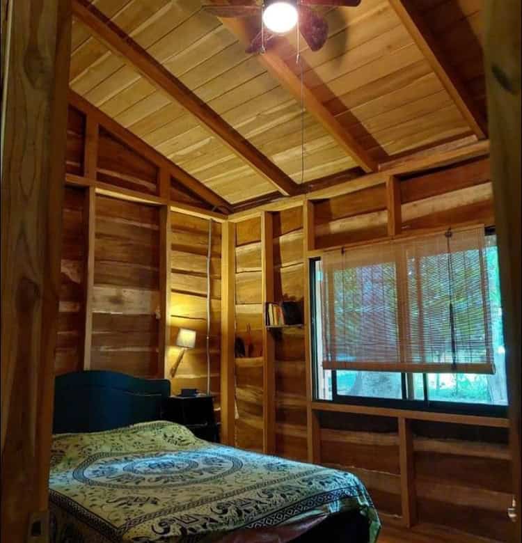Charming wooden bedroom with natural finishes in Vainilla, Costa Rica, featuring a ceiling fan and l.