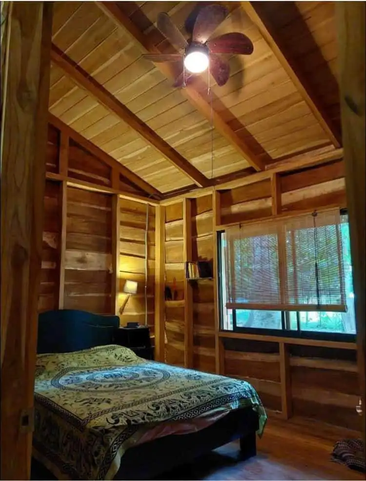 Charming wooden bedroom with natural finishes in Vainilla, Costa Rica, featuring a ceiling fan and l.