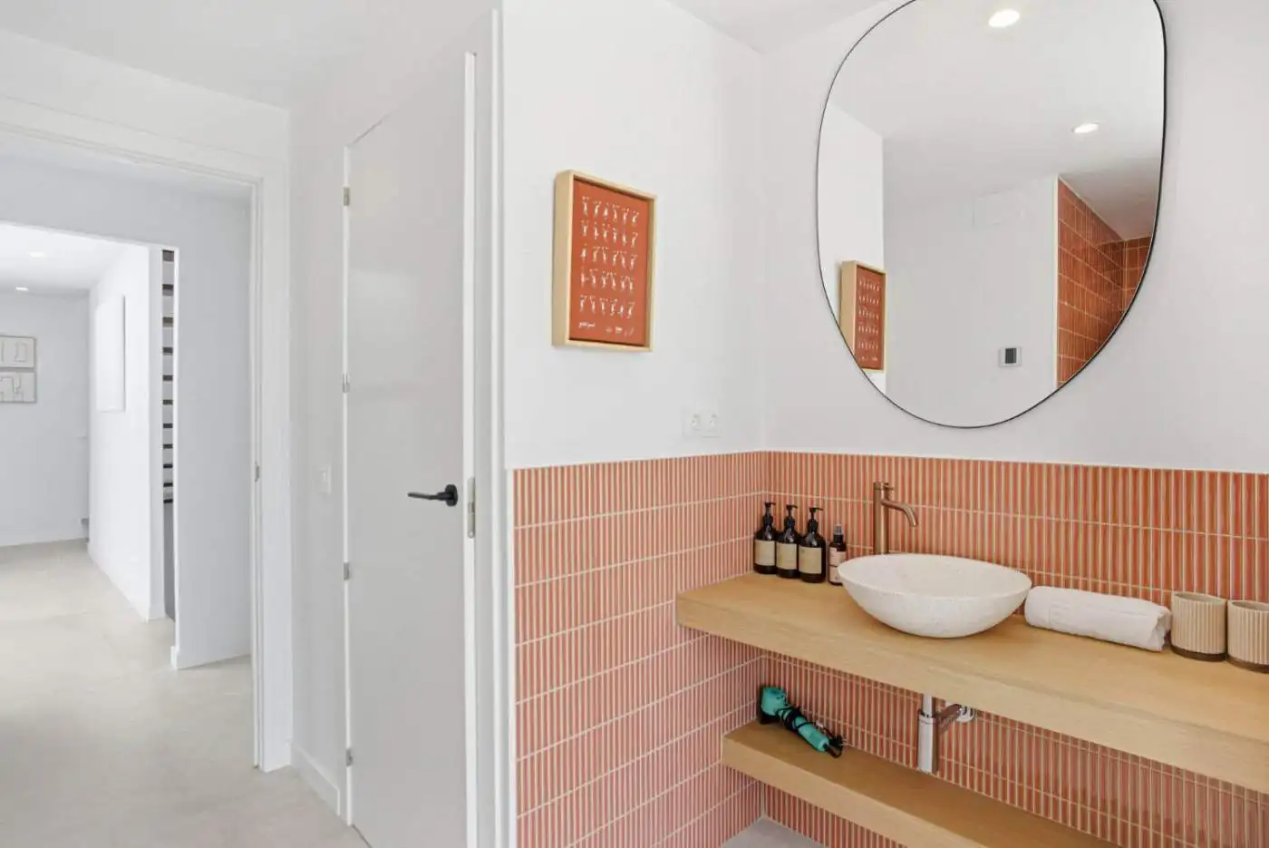 Bright and stylish bathroom featuring a round mirror and coral-colored tiles. Perfect for contempora.