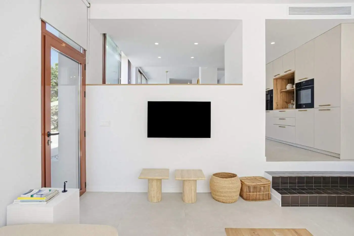 Wall-mounted TV in a bright, modern living room with minimalist furniture and natural accents.