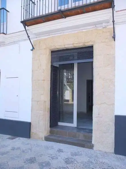 Apartment entrance with glass door and black shutters in a renovated building.