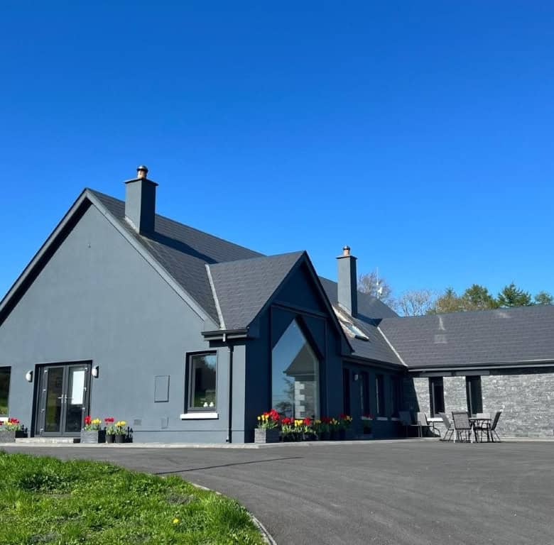 Contemporary grey house with large windows and a spacious driveway, set on a scenic 30-acre estate w.