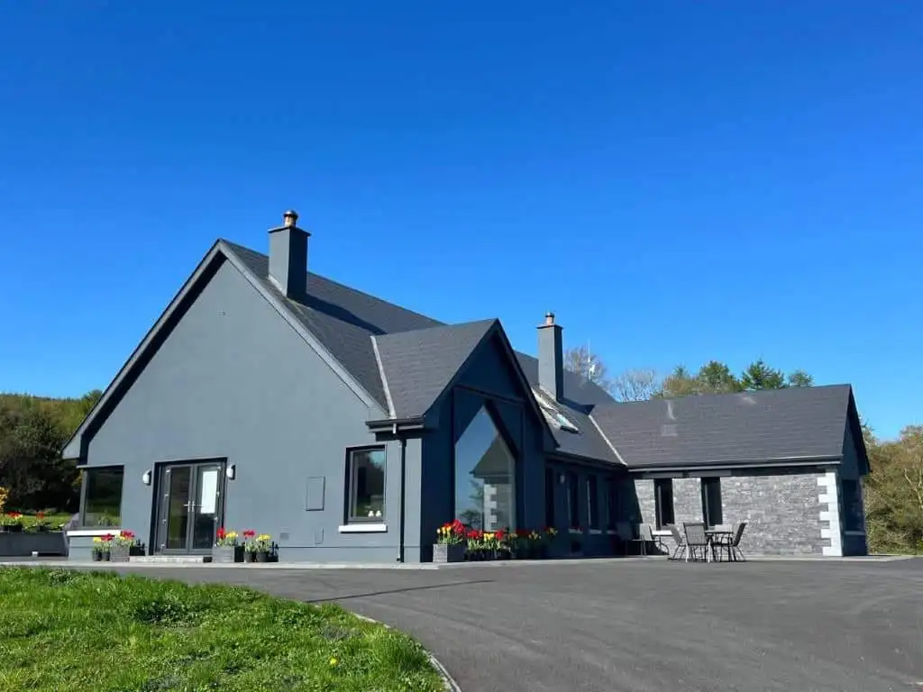 Contemporary grey house with large windows and a spacious driveway, set on a scenic 30-acre estate w.