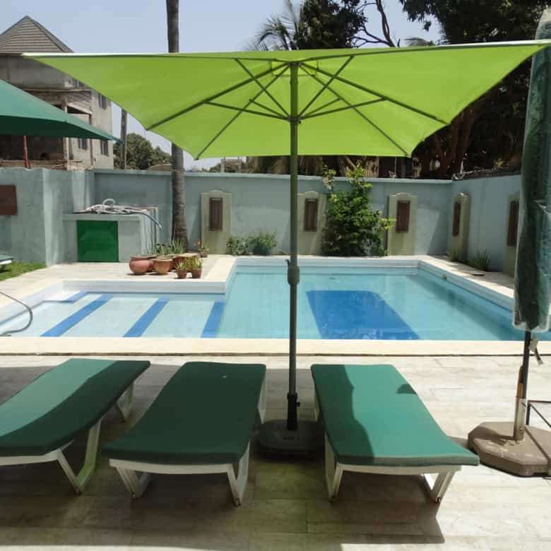 Poolside lounge with umbrellas and sunbeds at a charming bed and breakfast in Kombo North.
