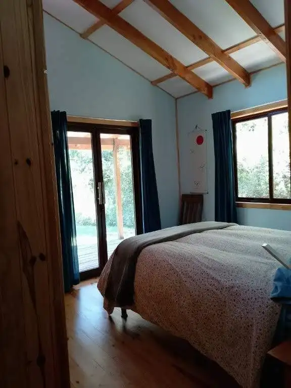 Beautiful bedroom at Hush Valley Estate with wooden beams and large windows in Rio Blanco, San Jose,.