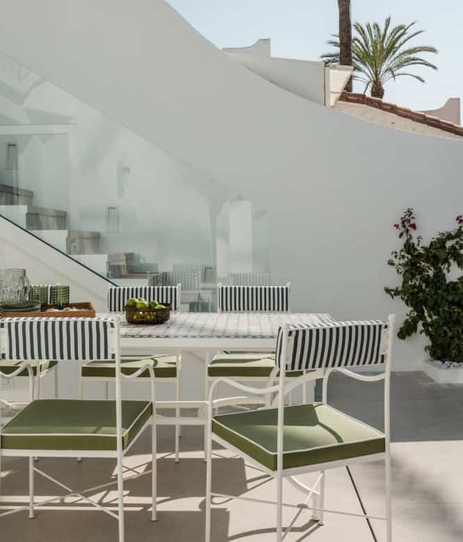 Elegant outdoor terrace with white furniture and striped cushions overlooking the sea.