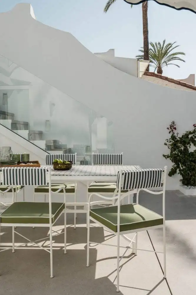 Elegant outdoor terrace with white furniture and striped cushions overlooking the sea.
