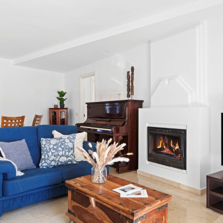 Bright living room featuring a fireplace, blue sofa, and contemporary furnishings in a stylish home.
