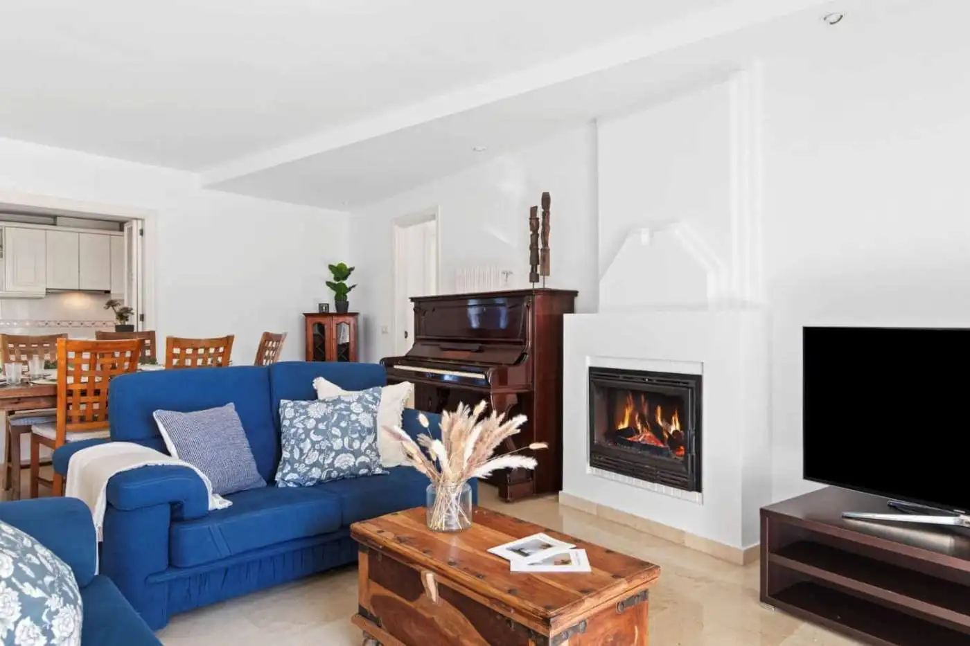 Bright living room featuring a fireplace, blue sofa, and contemporary furnishings in a stylish home.
