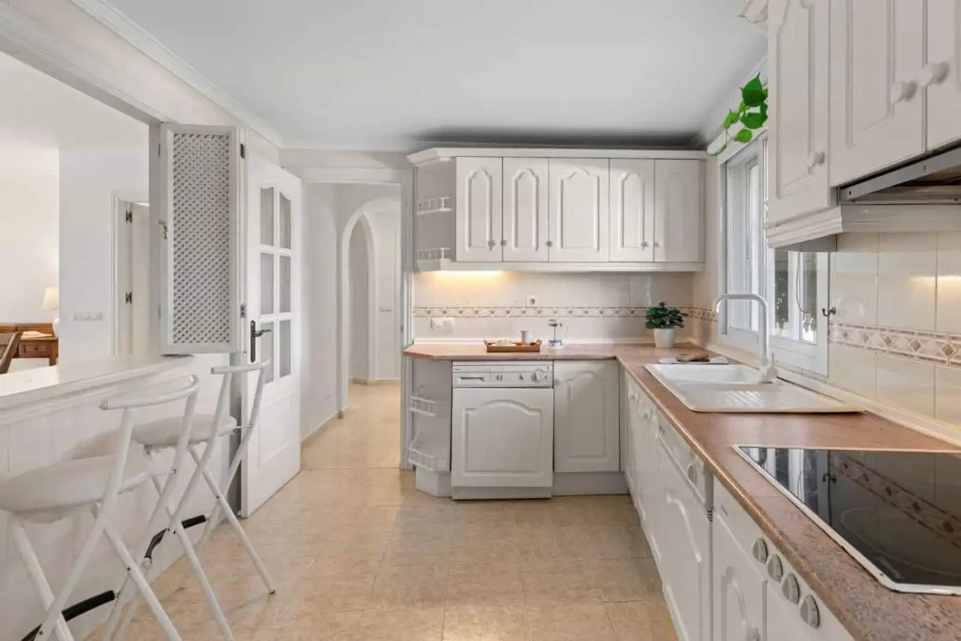 White kitchen with sea view and natural light, featuring cabinetry, countertops, and appliances.