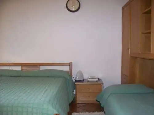 Hotel room interior with a double bed and a single bed, wooden furniture, and minimal decor near Lak.