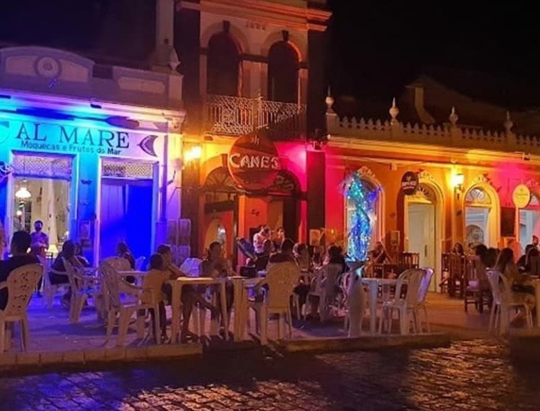 Vibrant illuminated buildings with outdoor dining in Canavieiras, Bahia, Brazil.