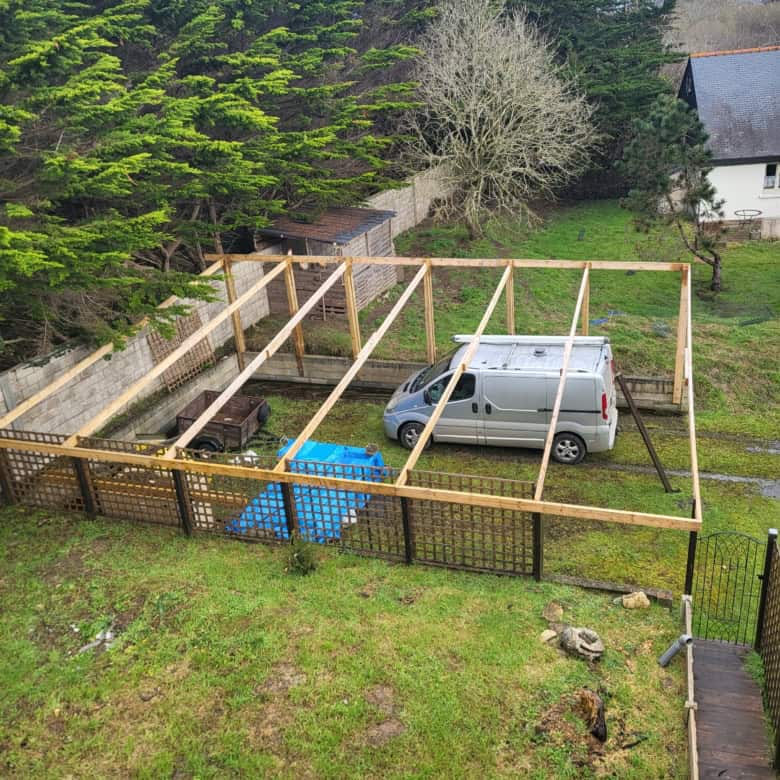 Attic construction site with wooden framework and parked van.
